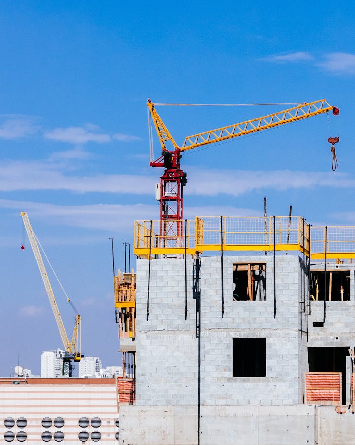 Red and Yellow Tower Crane on Top of Building Under Construction